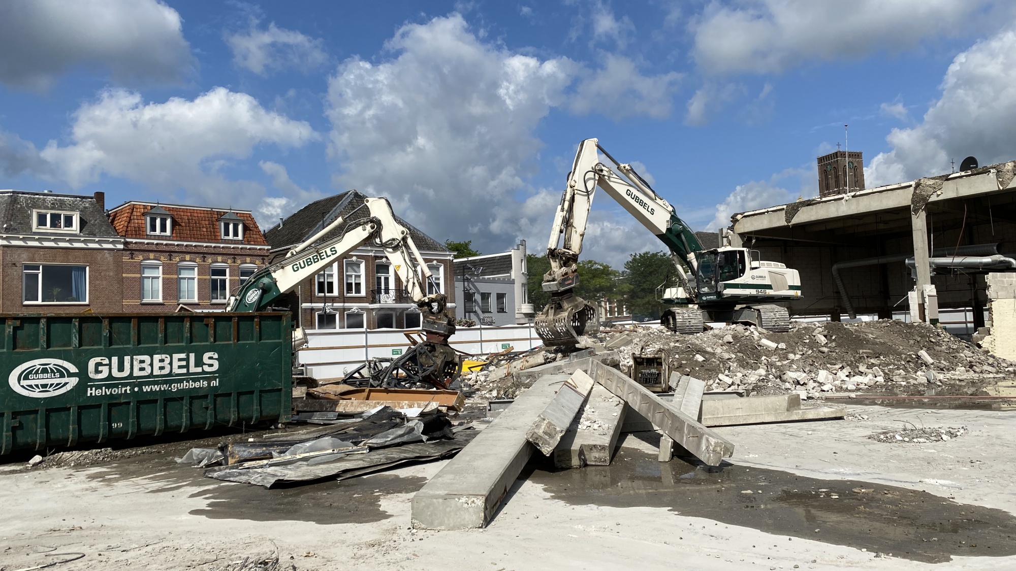 Twee graafmachines graven in het puin.