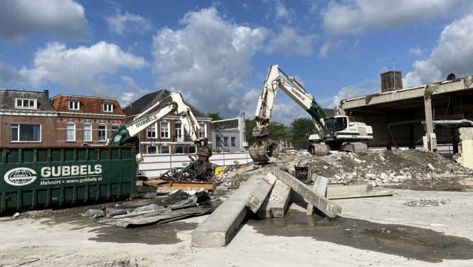 Twee graafmachines graven puin bij elkaar.