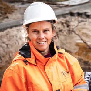 Juliette draagt een helm en veiligheidshesje.