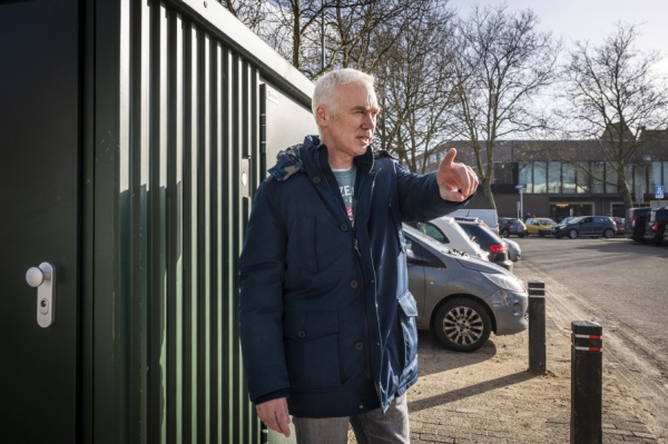 Patrick wijzend voor een container 